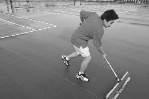 No. 1 boys singles player Justin Wu pushes a roller across the rain-soaked tennis courts at Renton High School as the team prepares for a match against Highline High School.