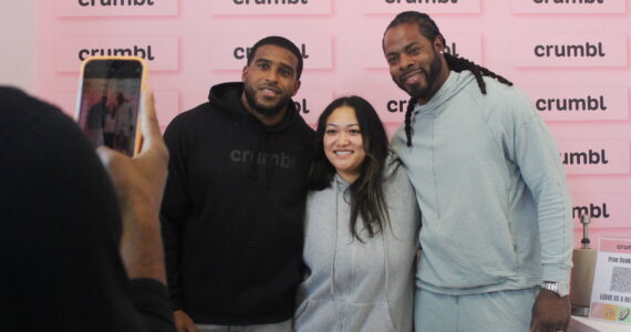 Bobby Wagner and Richard Sherman pose for a photo with a fan on the opening day of Crumbl Cookies, which Wagner co-owns. Photo by Bailey Jo Josie/Sound Publishing.