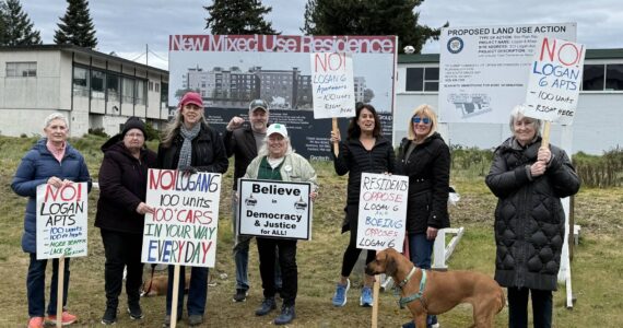 The Logan 6 protesters posed in front of signs detailing the new development planned for the lot between N. 3rd Street and 4th Street. Photo by Drew Dotson/Renton Reporter