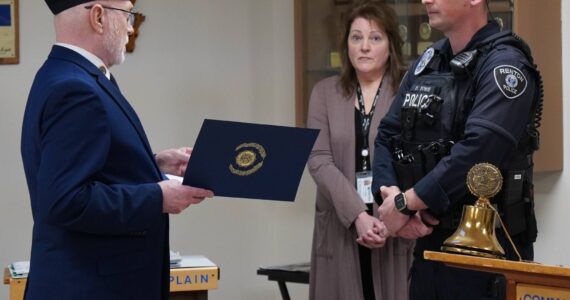An American Legion Post 19 member presenting a certificate to Officer Blake Bowie. Photo by Joshua Solorzano/The Reporter