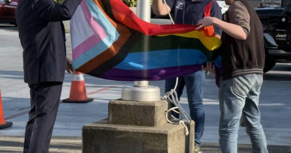 Renton Mayor Armondo Pavone (left) and Renton Pride representative Winter Cashman (right) unfurl the Pride flag. Photo by Drew Dotson/The Reporter