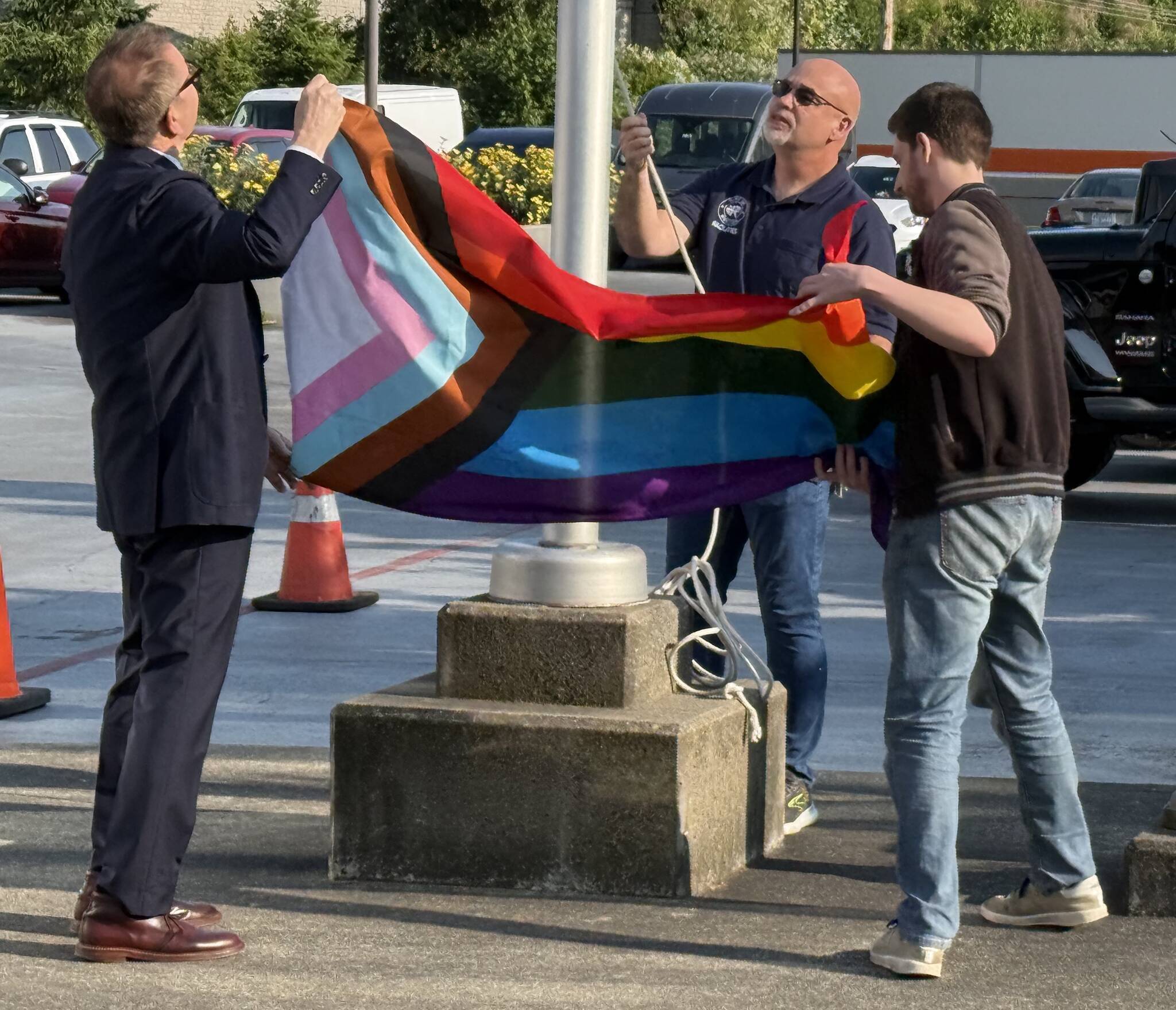 Renton Mayor Armondo Pavone (left) and Renton Pride representative Winter Cashman (right) unfurl the Pride flag. Photo by Drew Dotson/The Reporter