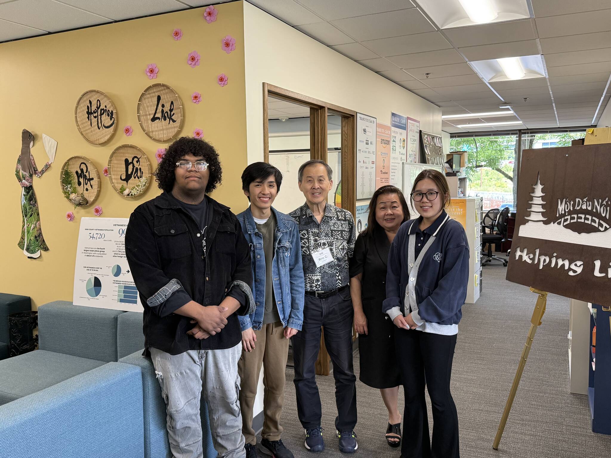 Executive Director Minh-Duc Nguyen (center right) and Ron Choi (center) rely on the work of volunteers to keep Helping Link running. Photo by Drew Dotson/Renton Reporter